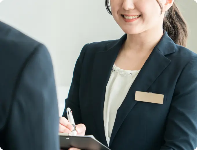 フロントで来客対応をしながらメモを取るスタッフ