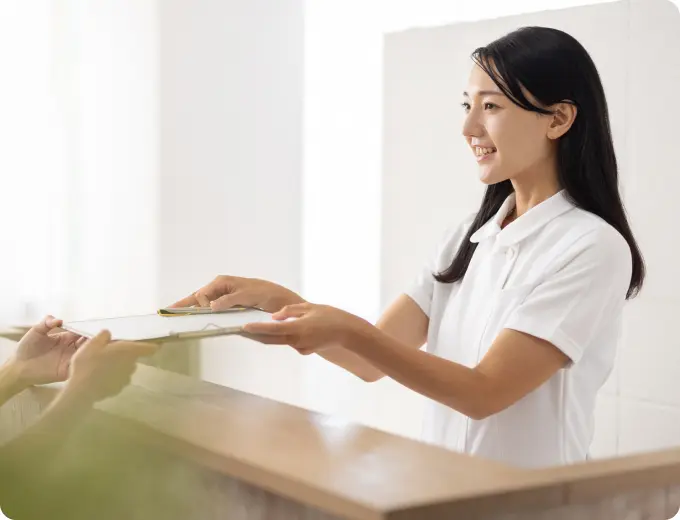 病院の受付で書類を手渡す医療スタッフ