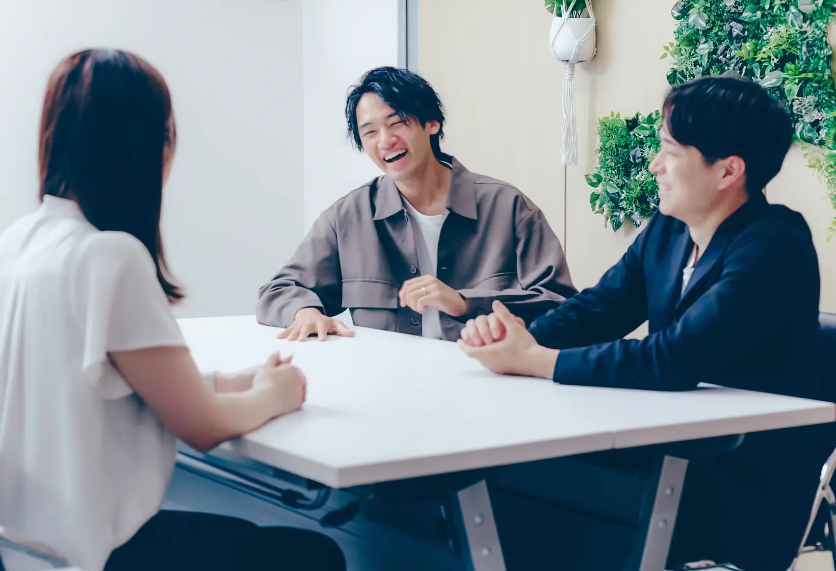 テーブルを囲んで談笑する3人の社員