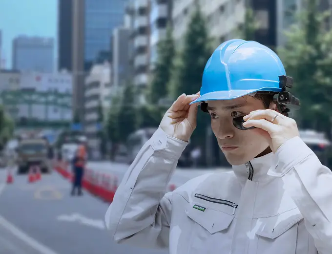 スマートグラスを装着し事務所から遠隔支援を受ける建設現場の作業員